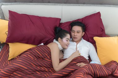 Genç Asyalı çift yatakta uyuyor ve sarılıyorlar.