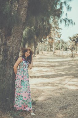 Çingene bir bohem gibi giyinmiş mutlu Asyalı bir kadın çam ormanında kafasında hasır bir şapka, iyi bir ruh hali kızı yaşam tarzı, klasik tarz, karanlık ton.