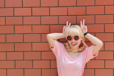 Taylandlı bir kadının portresi altın saçlar turuncu tuğla duvarda Japon tarzı, Asyalı bir kız açık havada fotoğraf çektirmek için poz veriyor.