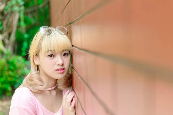 タイの女性黄金の髪の肖像オレンジレンガの壁に日本スタイル アジアの女の子のポーズ写真屋外で撮る — ストック写真