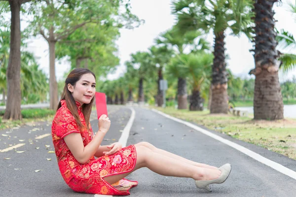 幸せな中国の新年 アジアの女性は 伝統的な清サム服の赤い封筒を着て道路の肖像画の屋外に座る — ストック写真