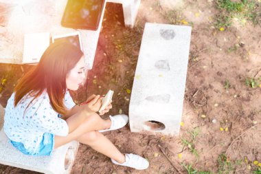 Parkta parlak güneş ışığıyla günlük yazan güzel Asyalı kadın.