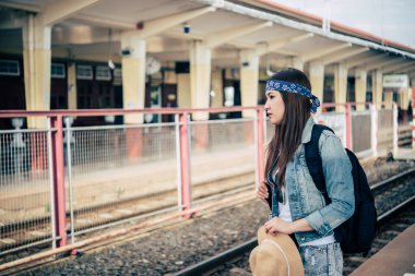 Asyalı turist tren istasyonunda bekliyor. Taylandlı hippi kadın seyahate çıkıyor.