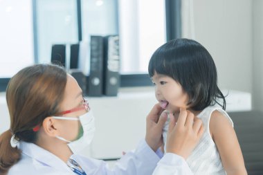 Solunumunu ve kalbini kontrol etmek için steteskop kullanan Asyalı bir doktor, Taylandlı çocukların sağlığını kontrol ediyor.