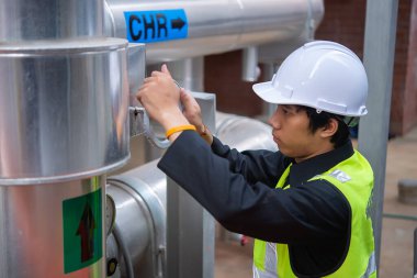 Büyük bir fabrikanın atık su yönetim sisteminde Asya Bakım Mühendisi, Tayland 'daki ısıtma sistemi ekipmanlarının teknik verilerini kontrol ediyor.