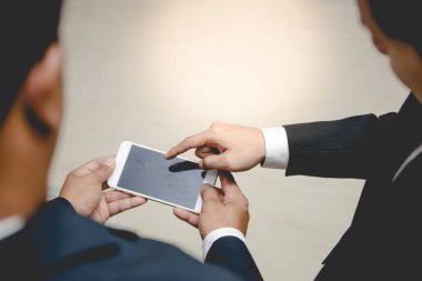 İki işadamı internetten kontrol işi için akıllı telefon kullanıyor, proje ve Taylandlılar hakkında tartışıyorlar.