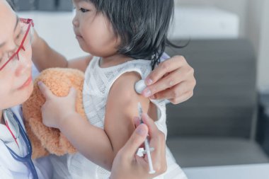 Solunumunu ve kalbini kontrol etmek için steteskop kullanan Asyalı bir doktor, Taylandlı çocukların sağlığını kontrol ediyor.