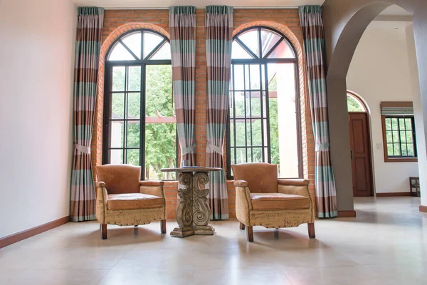 Oturma odasındaki lüks deri sandalyeler yan pencereler, perdeler, lüks uzunluklar..