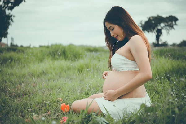 出産の近くに腹の中にある彼女の子供の音女性の腹のヘッドフォンはすでに パステル フィルムトーン ヴィンテージ — ストック写真