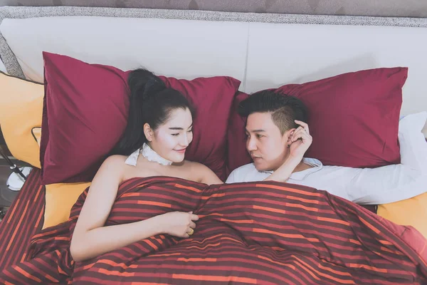 Young asian couple looking eyes together in bed