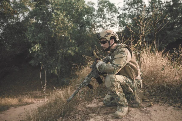 拿着枪的士兵坐在森林里 他在用对讲机呼叫支援 军事上的战争概念 — 图库照片
