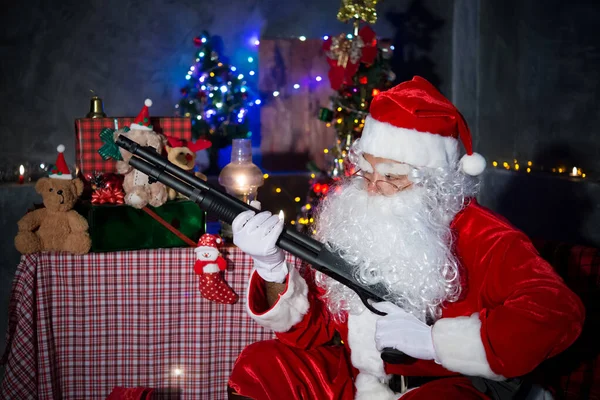愤怒的圣诞老人在家里拿着短枪 坐在椅子上考虑送孩子礼物的计划 — 图库照片