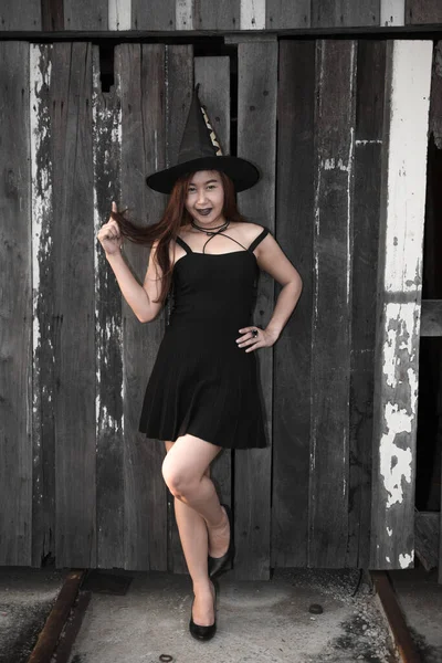 アジアの美しい女性は魔女の帽子 ハロウィーンのコンセプトと黒のドレスを身に着けている — ストック写真