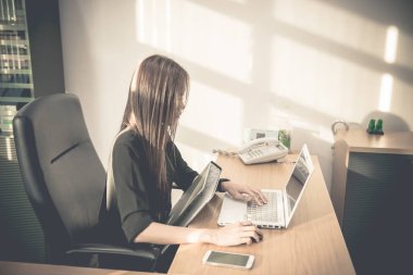 Asyalı memur kadın ofisteki dosyadan siparişleri kontrol ediyor.