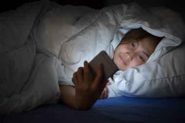Asyalı kadın gece yatakta akıllı telefon çalar, Taylandlılar...
