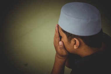 Genç bir Asyalı Müslüman gün batımında dua ediyor, Ramazan festivali konsepti.