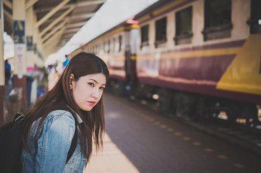 Asyalı bayan turist tren istasyonunda bekleyip seyahate çıkıyor.