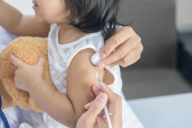 Solunumunu ve kalbini kontrol etmek için steteskop kullanan Asyalı bir doktor, Taylandlı çocukların sağlığını kontrol ediyor.