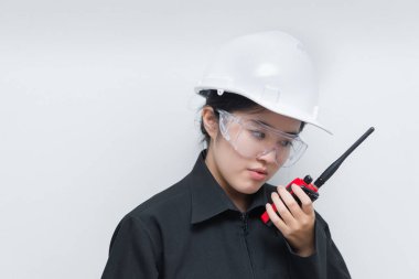 Happy Asian engineer woman wearing glasses,using radio communication on white background,thailand technician use walkie talkie for work clipart