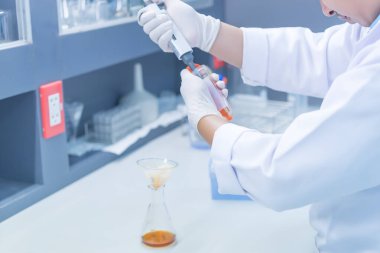 Bilim adamı deneyden önce kimyasalları sallama makinesiyle karıştırdı. Laboratuvarda çalışan Tayland 'lı bilim adamı test tüplerine numuneler karıştırdı.