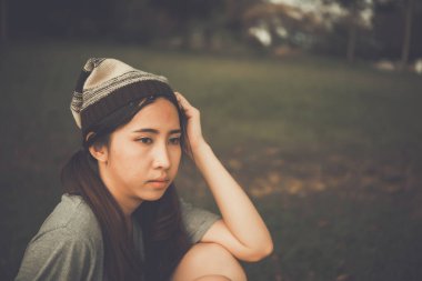 Yalnız Asyalı kadın parkta tek başına oturuyor, üzgün Taylandlı kadın bir şeyler düşünüyor, kalbi kırık kız konsepti.