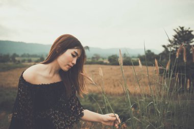 Güzel Taylandlı kadın çiçek çimlerine dokunur, karşılıksız aşktan çok üzgün, tekrar düşün, düşün, eski tarz, karanlık ton, kırık kalp, Asyalı kız