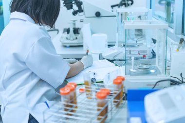 İki bilim adamı laboratuvarda deney yapıyor. Numunelerle karıştırılıp test tüplerine konuyor. Tayland 'lı bilim adamı laboratuarda çalışıyor.