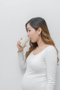 Elinde sütle hamile bir kadın, hamilelik için sağlıklı süt içiyor.