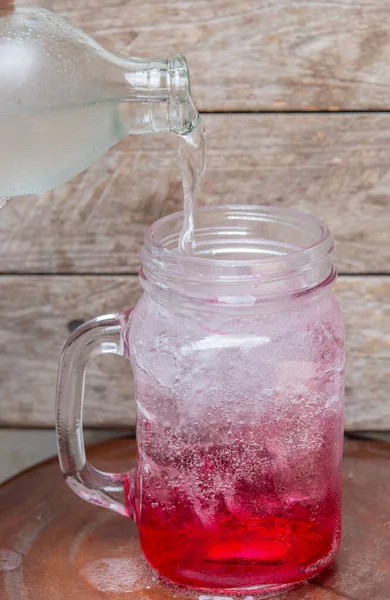 Pour soda for mix with red water in glass,fizzy