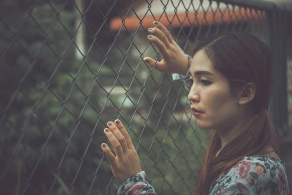 Portrait of sad woman  she touch fence and think something vintage style,dark tone