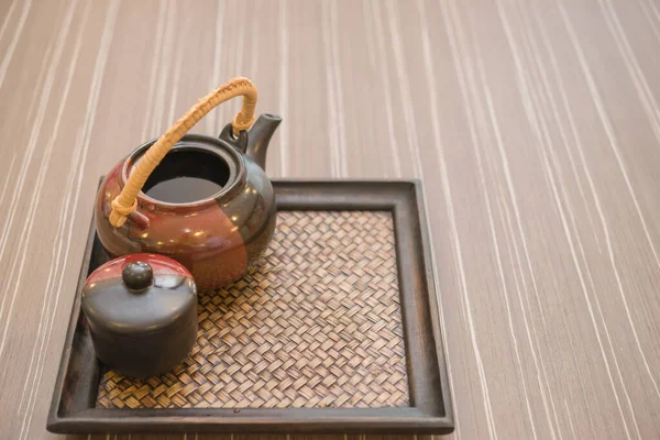 晴れた日には 木のテーブルの上に 明るい日差しの中で織られた盆竹の上にお茶のポット — ストック写真