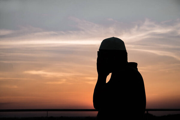 Силуэт Молодой азиат мусульманин молится на закате, Рамадан концепции фестиваля
