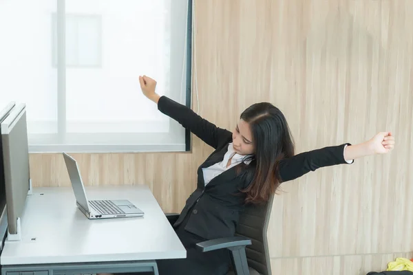 Asian officer woman stretching body at the desk of office from back angle,Thailand people,Businesswoman tired from hard work