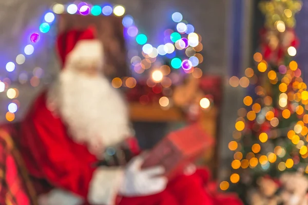 Blurry of Santa claus holding gift box at home,Sit on chair think about plan for sent gift box for give children