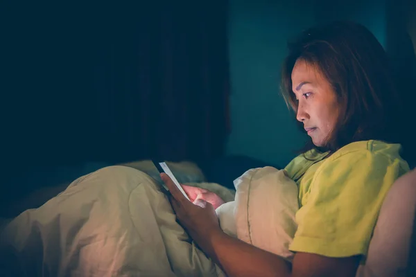 Asyalı kadın gece yatakta akıllı telefon oynuyor, Taylandlılar, sosyal medya bağımlısı, bütün gece internet oynuyor.