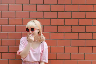 Taylandlı bir kadının portresi altın saçlar turuncu tuğla duvarda Japon tarzı, Asyalı bir kız açık havada fotoğraf çektirmek için poz veriyor.