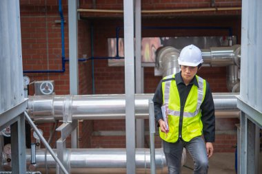 Büyük bir fabrikanın atık su yönetim sisteminde Asya Bakım Mühendisi, Tayland 'daki ısıtma sistemi ekipmanlarının teknik verilerini kontrol ediyor.