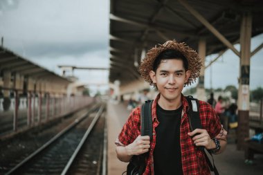 Asyalı turist tren istasyonunda bekler, Taylandlı hippi gezmeye gider.