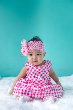 Pembe elbiseli şirin Asyalı bebek portresi, halı yünü, mutlu bebek konsepti, gülümseme, bıldırcın küçük bebek