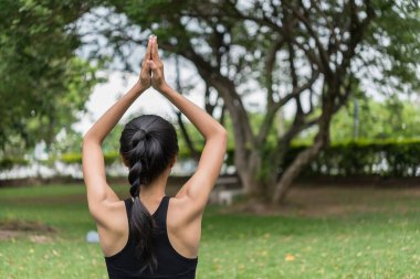 Sıska kız parkın çimlerinde yoga yapıyor, doğal olarak rahatlıyor, Asyalı kızlar yoga yapmaya bayılıyor.