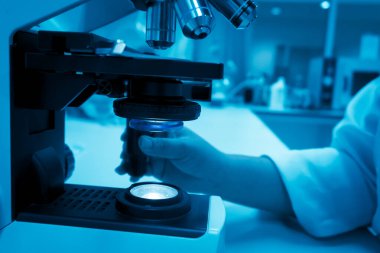 Genç Asyalı bilim adamı bir laboratuarda mikroskoptan bakıyor. Taylandlılar biraz araştırma yapıyor..