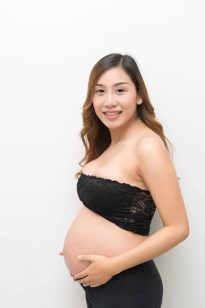 白い背景に白いドレスの妊婦が腹に触れアジアの女性が — ストック写真