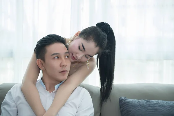 Asian couple in living room, woman hugging man from back