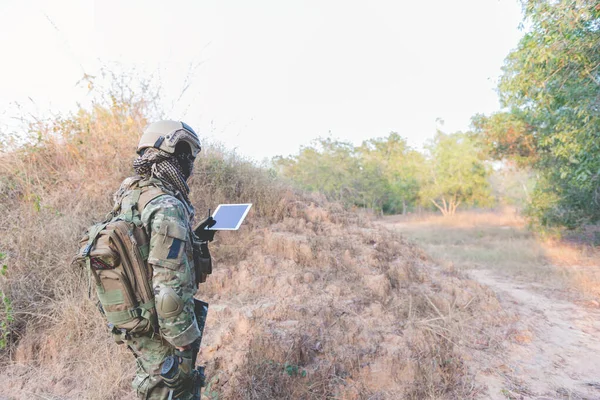 Soldier using map on tablet for orientation at forest