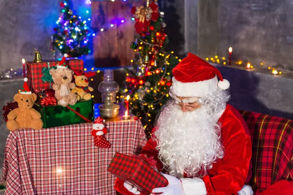 Santa claus holding gift box at home,Sit on chair think about plan for sent gift box for give children