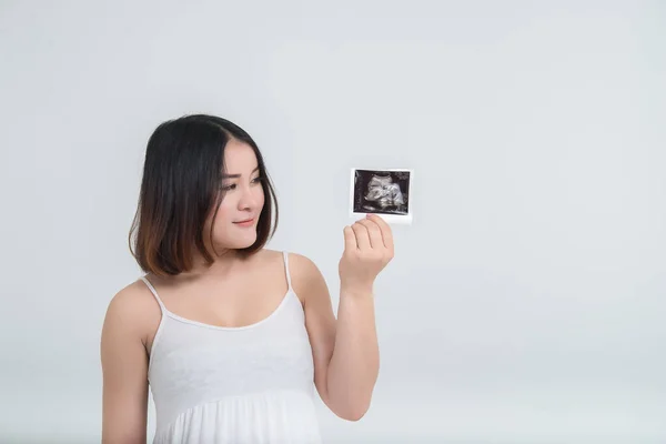 Beautiful asian pregnant woman with ultrasound photo in her hand,Thailand people on white background