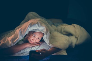 Asyalı kadın gece yatakta akıllı telefon oynuyor, Taylandlılar, sosyal medya bağımlısı, bütün gece internet oynuyor.