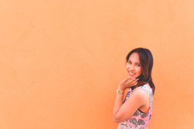 Güzel Asyalı kadın portresi turuncu duvara poz veriyor. Bekar bir kızın yaşam tarzı.