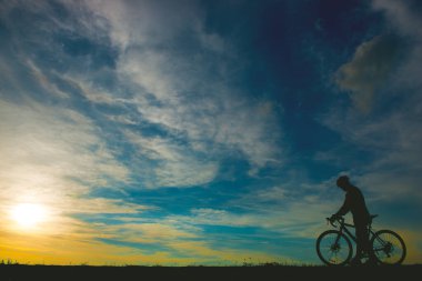 Gün batımında bisikleti olan yakışıklı bir adamın silueti, spor adamı konsepti.