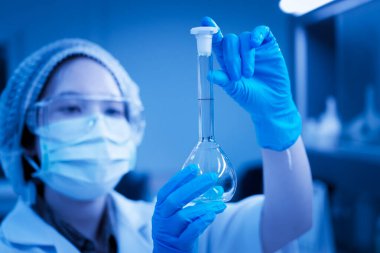 Büyük bir deney tüpü taşıyan Asyalı bilim adamları laboratuarda Tayland 'lı bilim adamı deneylerini hazırlıyorlar.